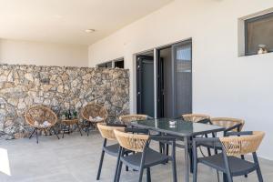 a patio with a table and chairs and a stone wall at Thalori villa 1 in Psalidi