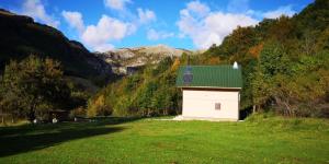 a small white building with a green roof in a field at Pridvorica in Gacko