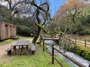 a picnic table and a bridge over a river at Grota Lodging in Leiria +3 photos