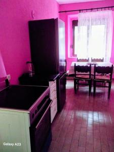 eine rosa Küche mit Herd und Tisch in der Unterkunft Apartment Dragone in Ulcinj