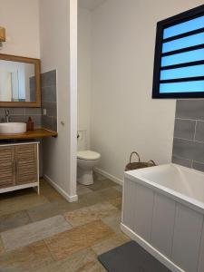 a bathroom with a tub and a toilet and a sink at Kaz mer veille in Les Avirons +4 photos