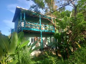a blue house with a balcony in the forest at Roatan Onat Hostel 1 in West End