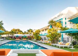 a pool with chairs and umbrellas in front of a hotel at The Vagabond Hotel Miami in Miami