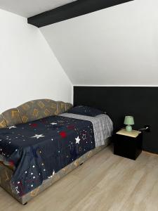 a bedroom with a bed with a comforter and a table at Casa Dany in Zărneşti +4 photos