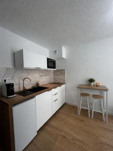 a kitchen with white cabinets and a sink and a table at Studio hesperides in Balaruc-les-Bains
