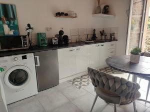 a kitchen with a washing machine and a table at La Suite 27 bis, maison de charme avec terrasse, proche gare et centre in Guingamp
