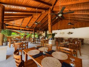a restaurant with wooden ceilings and tables and chairs at Hotel Playa Espadilla in Manuel Antonio