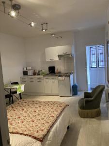 a bedroom with a bed and a chair and a kitchen at STUDIO hyper centre in Bagnoles de l'Orne