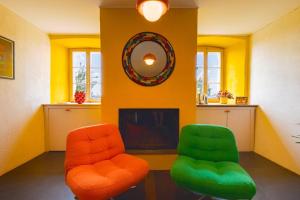 two orange and green chairs in a room with a tv at Farm & Chill Guesthouse in Thierrens