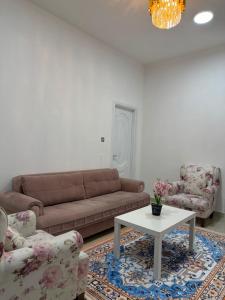 ein Wohnzimmer mit einer Couch, zwei Sesseln und einem Tisch in der Unterkunft Naforah in al-Ain