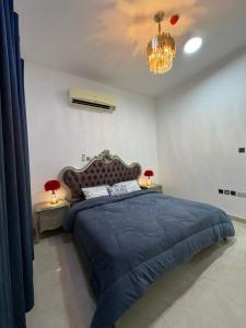 ein Schlafzimmer mit einem blauen Bett und einem Kronleuchter in der Unterkunft Naforah in al-Ain
