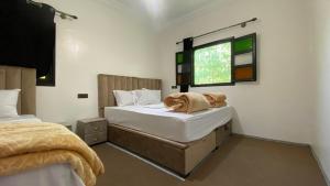 a bedroom with two beds and a window at Beldi apparemment in Imlil