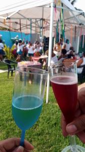 a person holding a glass of wine next to another at Casa de praia em Barra do Gil in Vera Cruz de Itaparica