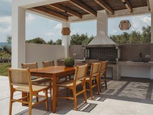 a wooden table and chairs on a patio with a fireplace at Serenita luxury villa in Zakynthos