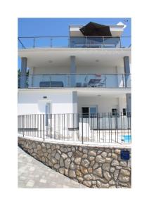 a house with a balcony and a stone wall at Villa Noah Apartement 2 in Novi Vinodolski