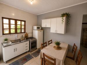 a kitchen with a table and a white refrigerator at GH Pinheira in Palhoça