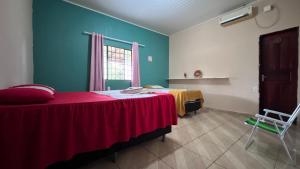 a bedroom with a bed with a red blanket and a window at Casa Lari Hostel in Vila Tepequém