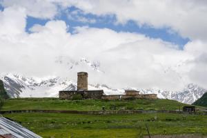 a building on a hill with a mountain in the background at Koruld Ushguli in Chvibiani