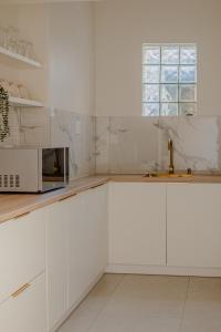 a white kitchen with a sink and a microwave at Sand In My Shoes in Muizenberg