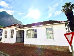 a white house with a palm tree and a yield sign at Sand In My Shoes in Muizenberg