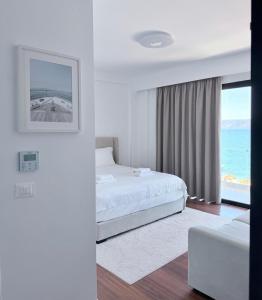 a white bedroom with a bed and a view of the ocean at Swiss Rivage Hotel in Vlorë