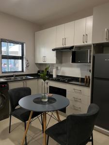 a small kitchen with a table and chairs and a refrigerator at The Kgale Luxe in Gaborone