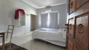 a bedroom with a bed and a chair and a door at Hotel Lara - Simolândia in Alvorada do Norte 