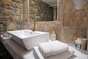 a bathroom with a white sink and a stone wall at Althaia in Ano Chora +88 photos
