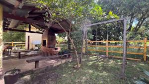 a wooden deck with a bench and a tree at Casa Lari Hostel in Vila Tepequém