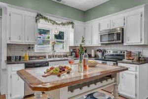 a kitchen with white cabinets and a table with a bowl of fruit at Lakefront Getaway with Dock, Pool, Sunset Games in Greenwood