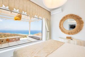 a bedroom with a large window with a view of the ocean at Mythos Villa Above the Sunset in Karpathos