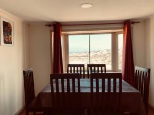 a dining room with a table and chairs and a window at Entre Dunas y Caracolas in Punta de Choros