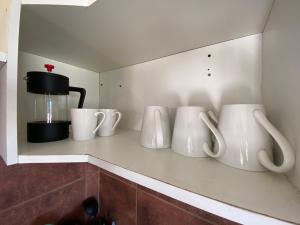 a row of white mugs sitting on a shelf at Entre Dunas y Caracolas in Punta de Choros