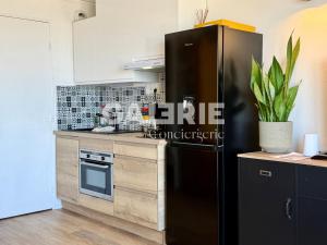 a kitchen with a black refrigerator and a stove at GC - Le Panorama - Front de Mer in Wissant