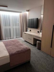 a hotel room with a bed and a desk and a television at No 11 Residence in Krynica Morska