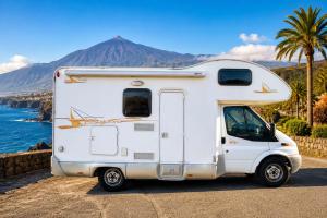 a white caravan parked next to the ocean at CamperTenerife in Callao Salvaje