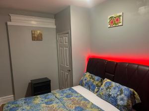 a bedroom with a bed with a red light at Stylish Red LED Bedroom in Irvington