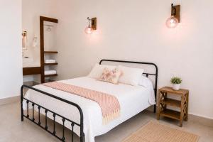 a bedroom with a bed with white sheets and pink pillows at Casa Feregrino Hotel Boutique in Cuatrociénegas de Carranza