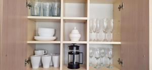 a cupboard filled with glasses and wine glasses at Deivido apartamentai Šiauliuose in Šiauliai