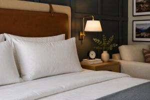 a bed with white pillows and a table with a clock at Stonebridge Inn in Snowmass Village
