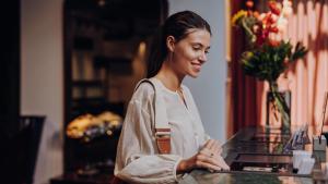 una donna seduta al bancone con un computer portatile di Ruby Lilly Hotel Munich by IHG a Monaco