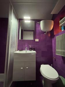 a bathroom with a sink and a toilet and purple tiles at Il tuo rifugio all' Argentario in Porto Santo Stefano