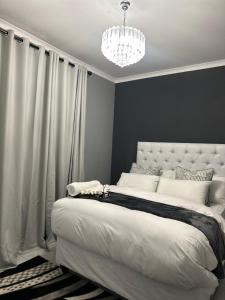 a bedroom with a large white bed with a chandelier at P Daisy in Rundu +3 photos