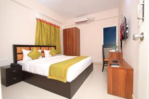 ein Schlafzimmer mit einem Bett, einem Schreibtisch und einem Fernseher in der Unterkunft Arra Grande Suites - Nearest Airport Hotels Bangalore in Devanhalli + 29 Fotos