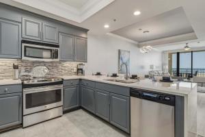 a large kitchen with gray cabinets and appliances at Luxury GulfFront Penthouse with Resort Amenities in Dauphin Island +22 photos