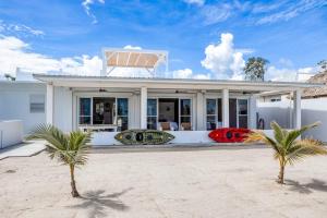 a white house with two palm trees in front of it at White Sands Beach House in Maya Beach