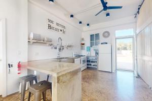 a white kitchen with a counter and a refrigerator at White Sands Beach House in Maya Beach