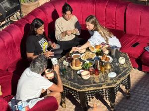 a group of people sitting around a table eating food at Farissi's Zawya Surf House in Aourir