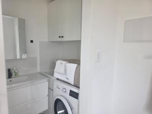 a white kitchen with a washing machine and a sink at Tiatukia Beach House in North Shields