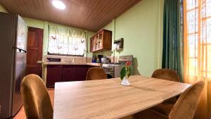 a kitchen with a wooden table with chairs and a refrigerator at Casa Pentagonia in Puerto Jiménez
